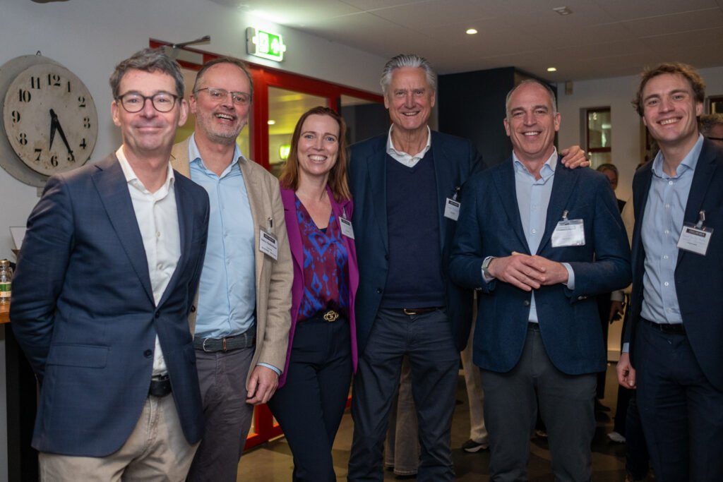 Groep lachende professionals poseert samen tijdens een netwerkbijeenkomst van Breikers.