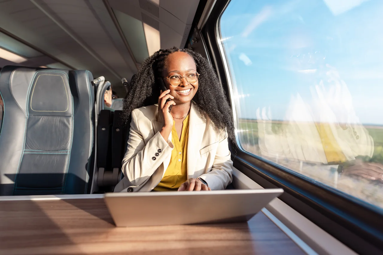Vrouw van Breikers belt in de trein terwijl ze werkt op haar laptop.